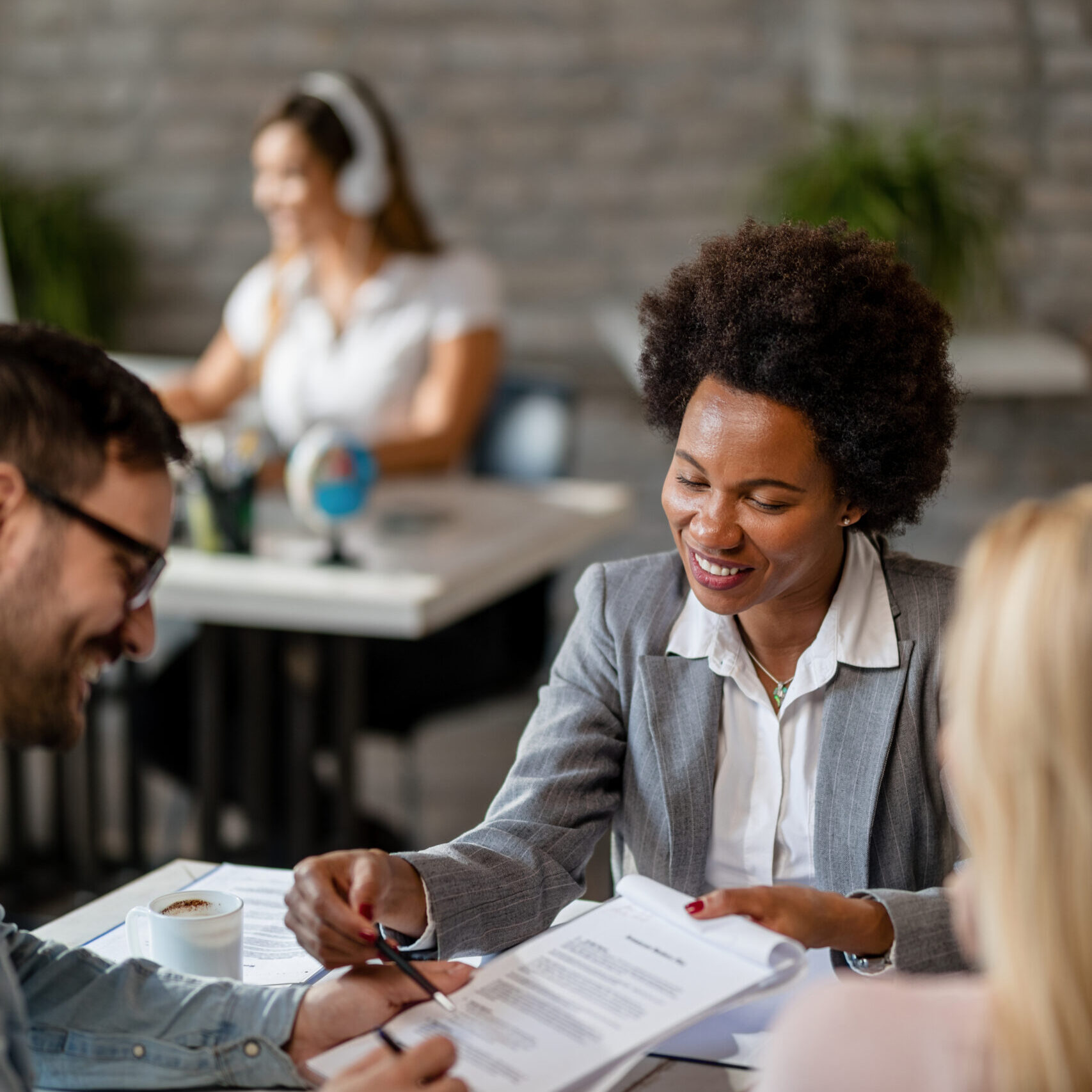 Happy African American insurance agent showing to a couple where to sign the contract. Black happy financial advisor closing a deal with a couple and pointing at the place they need to sign.